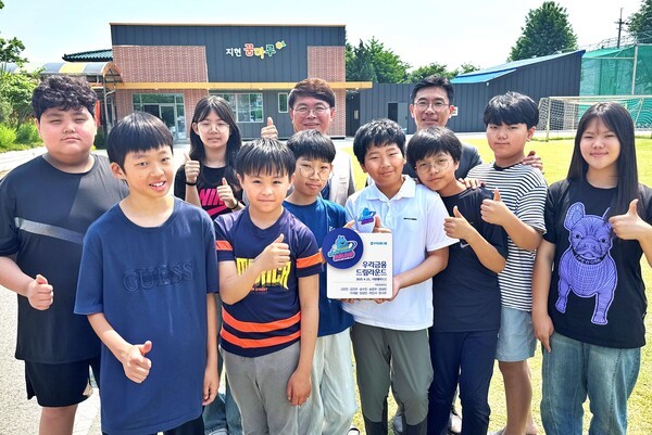 우리금융이 29일 경기 포천 지현초등학교에서 드림라운드 현판식을 개최했다. 지현초등학교 학생 9명과 이영신 교장(뒷줄 왼쪽에서 세번째), 우리금융지주 박준태 부장(뒷줄 왼쪽에서 네번째)이 기념 촬영을 하고 있다. [사진=우리금융 제공]